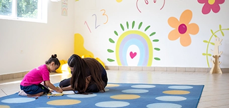 Niños sentados en mesas redondas en el aula.